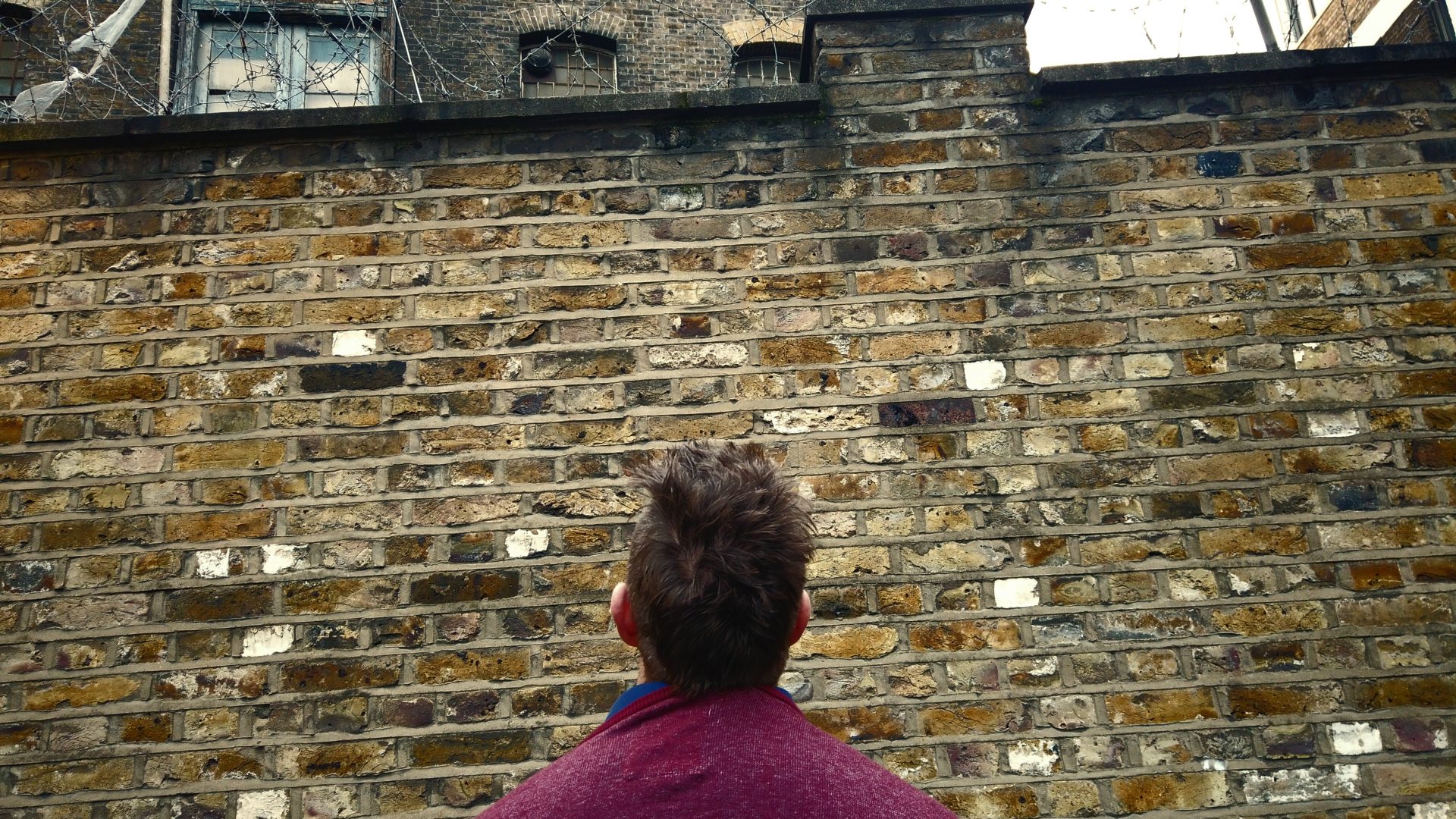 Picture of a man looking up at a prison wall