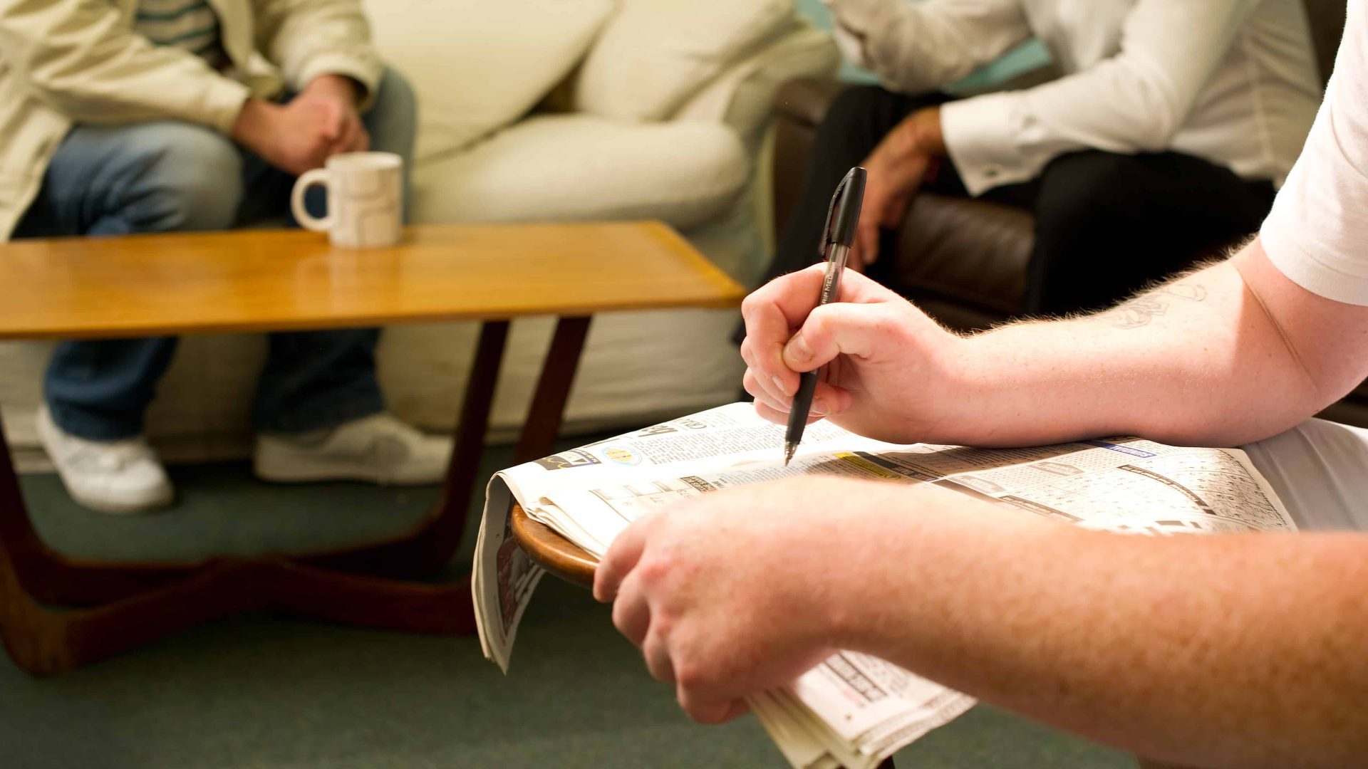 Person completing a crossword in a newspaper