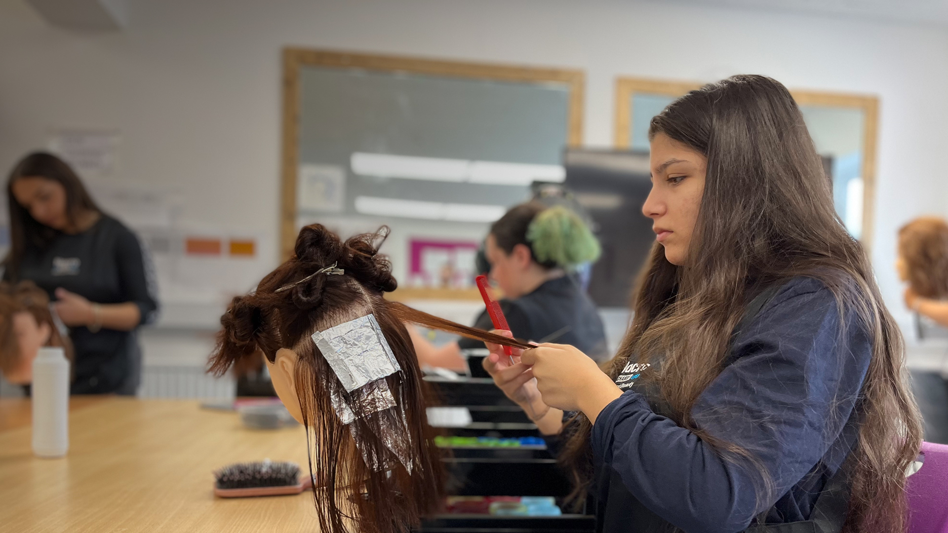 image of a learner practicing hairdressing for her course.
