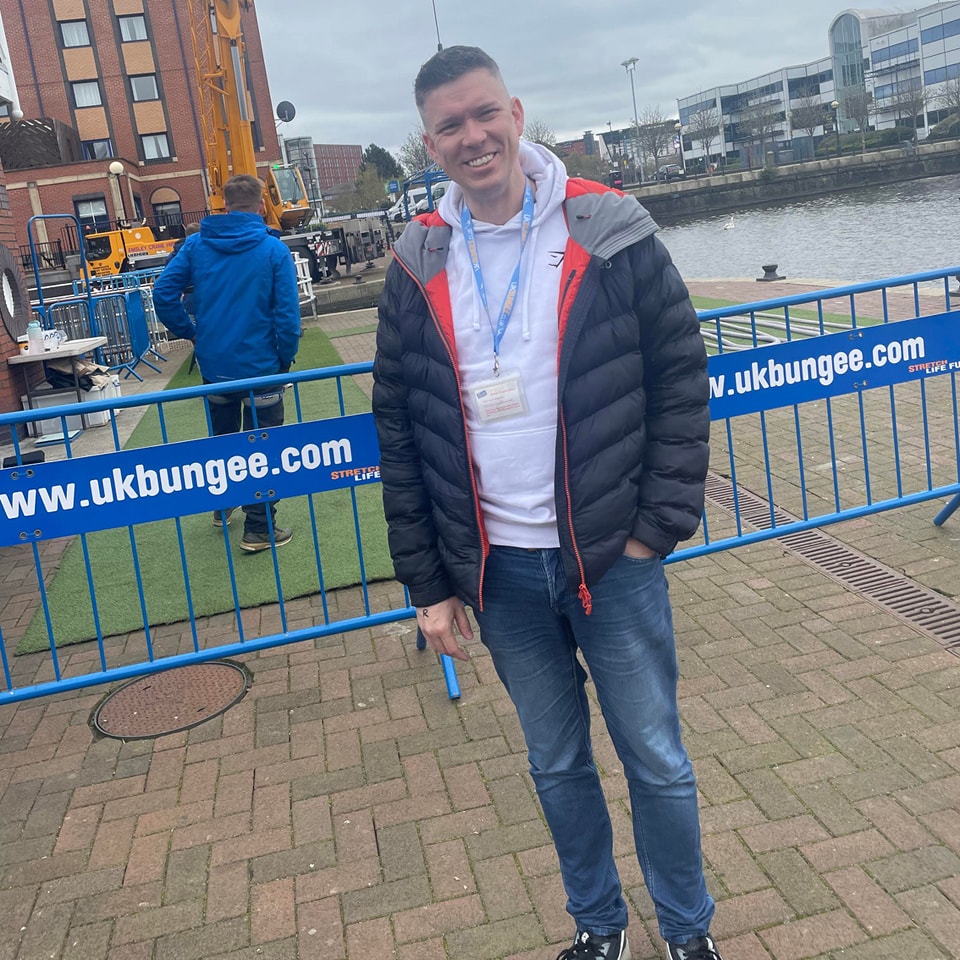 Man standing on Salford Quays wearing a puffa jacket, after a bungee jump.