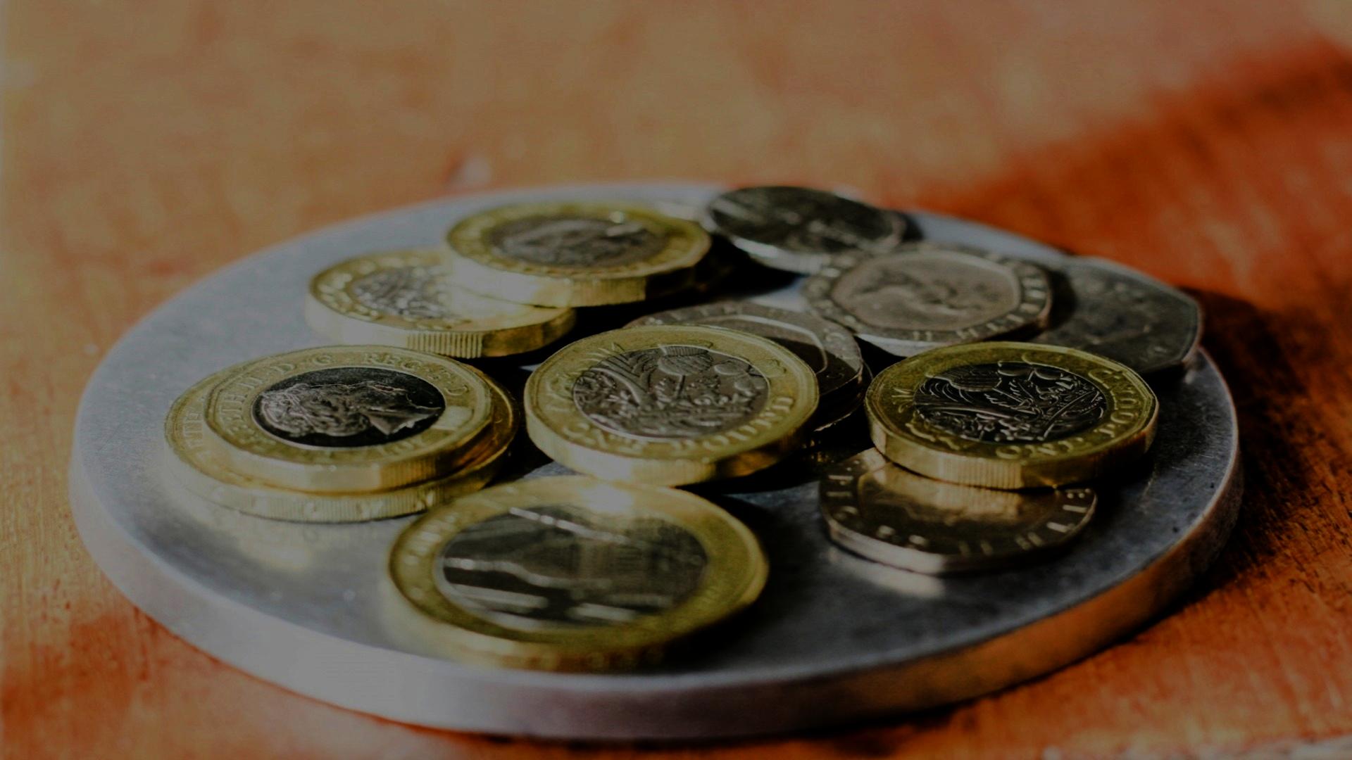 Image of money coins on a plate, on a table