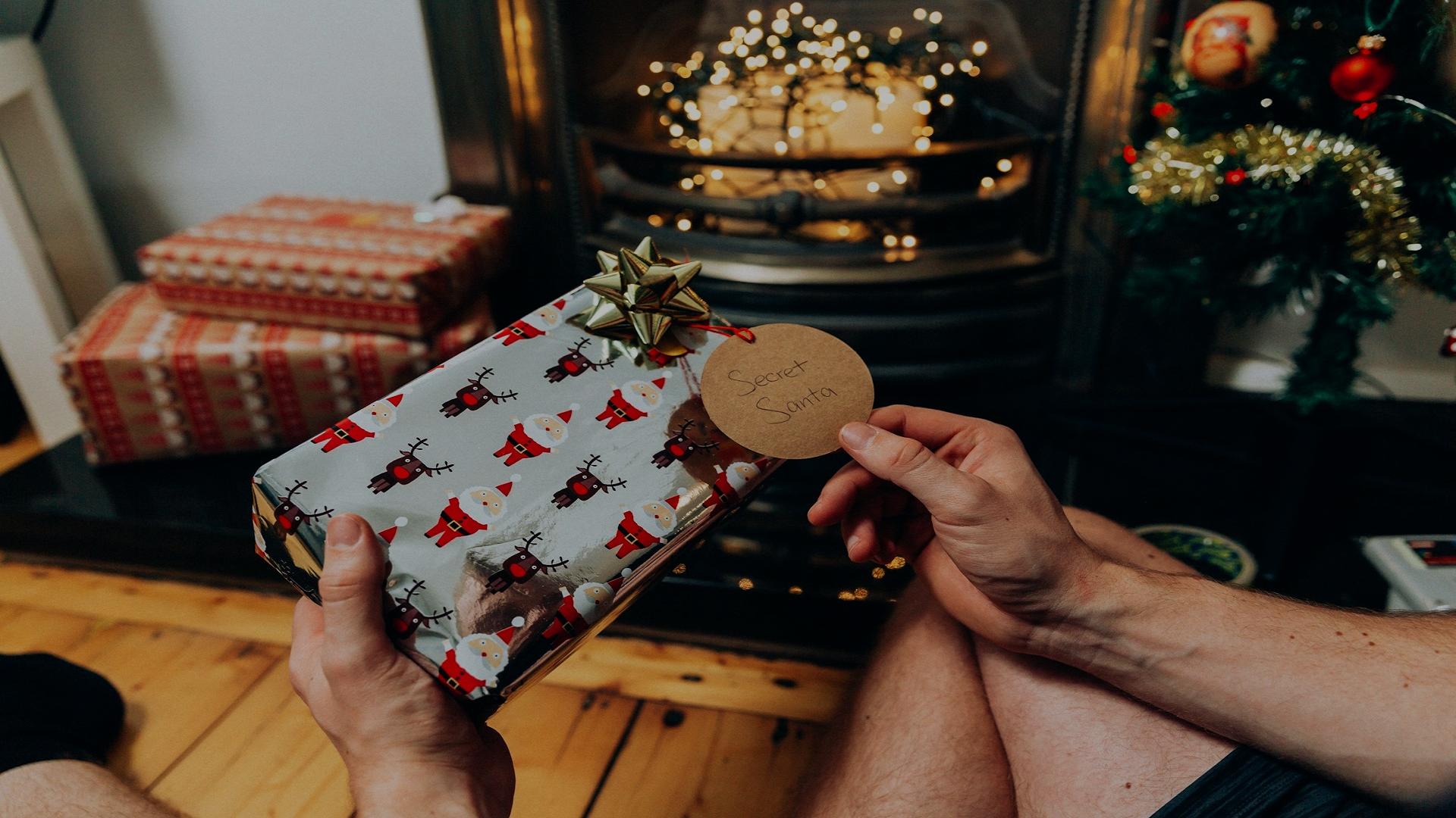 Image of a person holding a Christmas present with a Secret Santa label